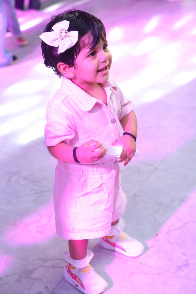 Toddler girl with white bow playing under purple rave lights